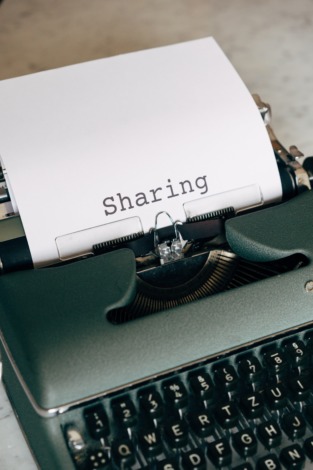 Bild einer Schreibmaschine mit dem Wort "Sharing" auf einem Blatt Papier